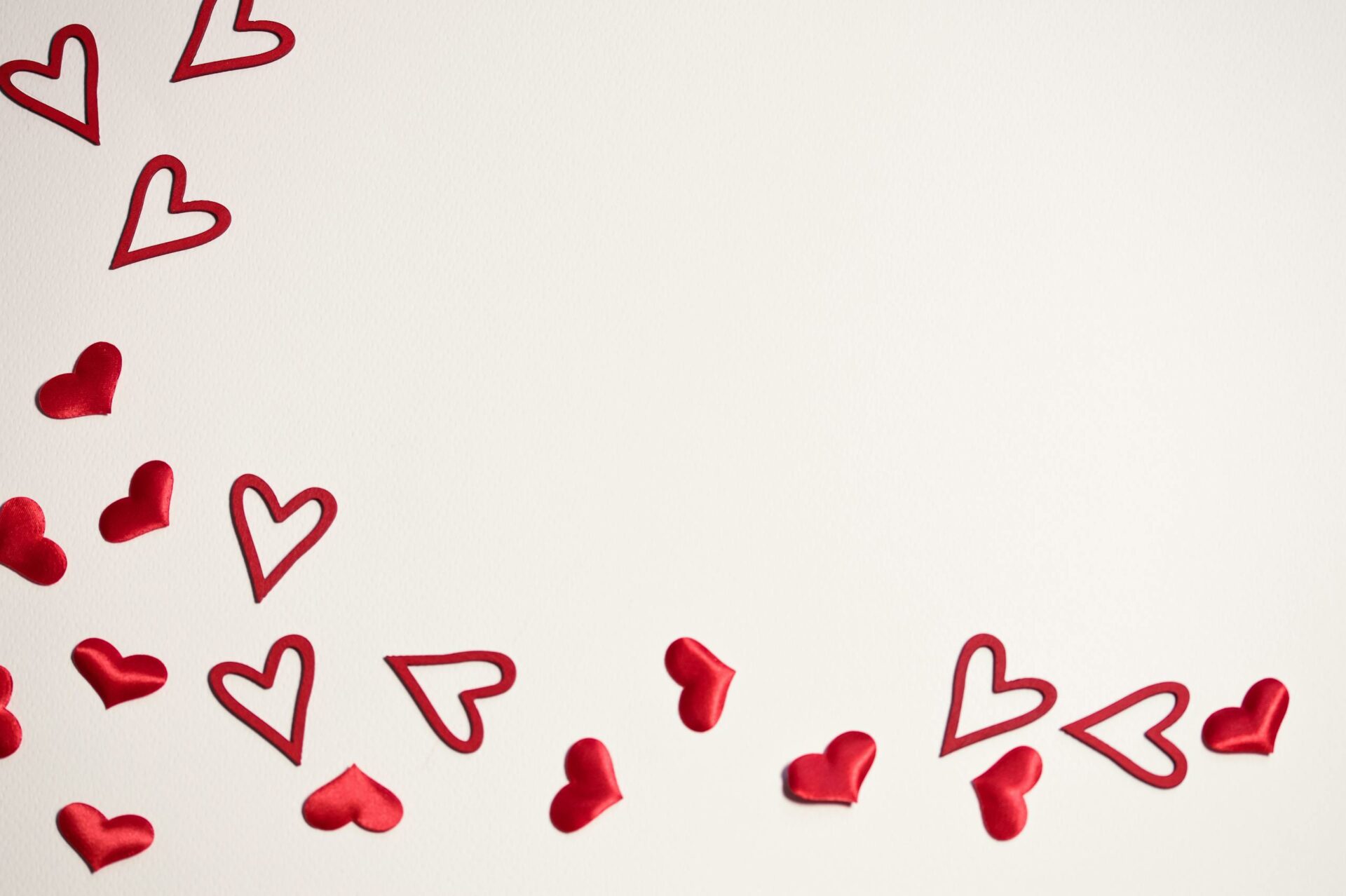 Red hearts scattered on a white background, ideal for Valentine's Day or romantic themes.